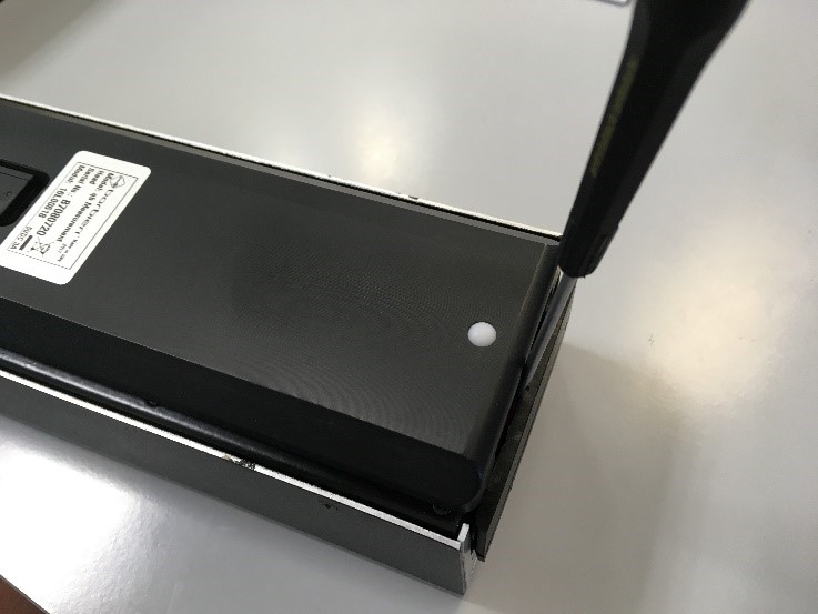 Battery holder released from the back of the spectral unit using a slotted screwdriver